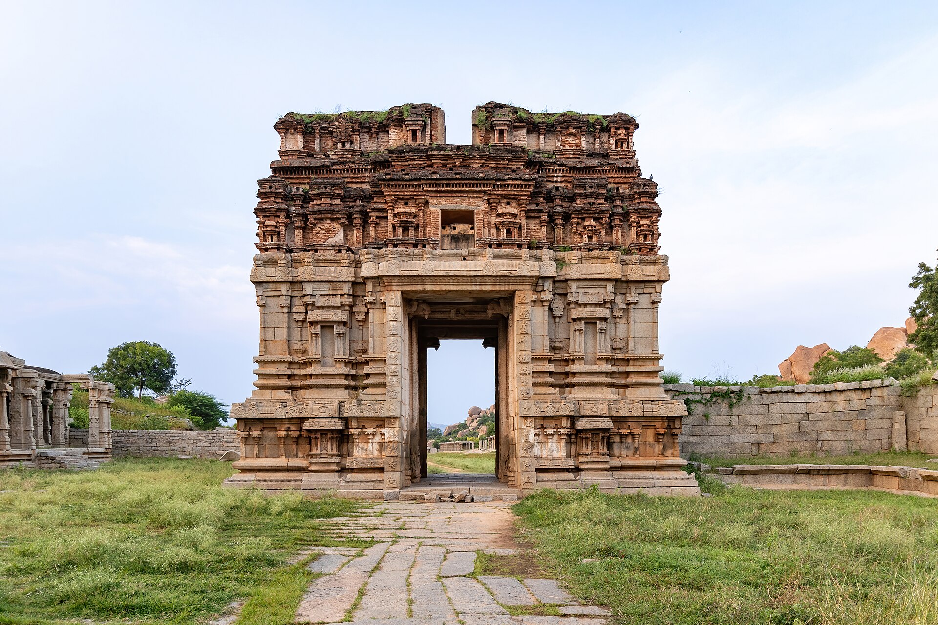 This wide-angle image showcases the Galigopuram of the Achyutaraya complex, emphasizing its impressive scale and intricate architectural details. The gopuram, a towering gateway adorned with elaborate carvings, reflects